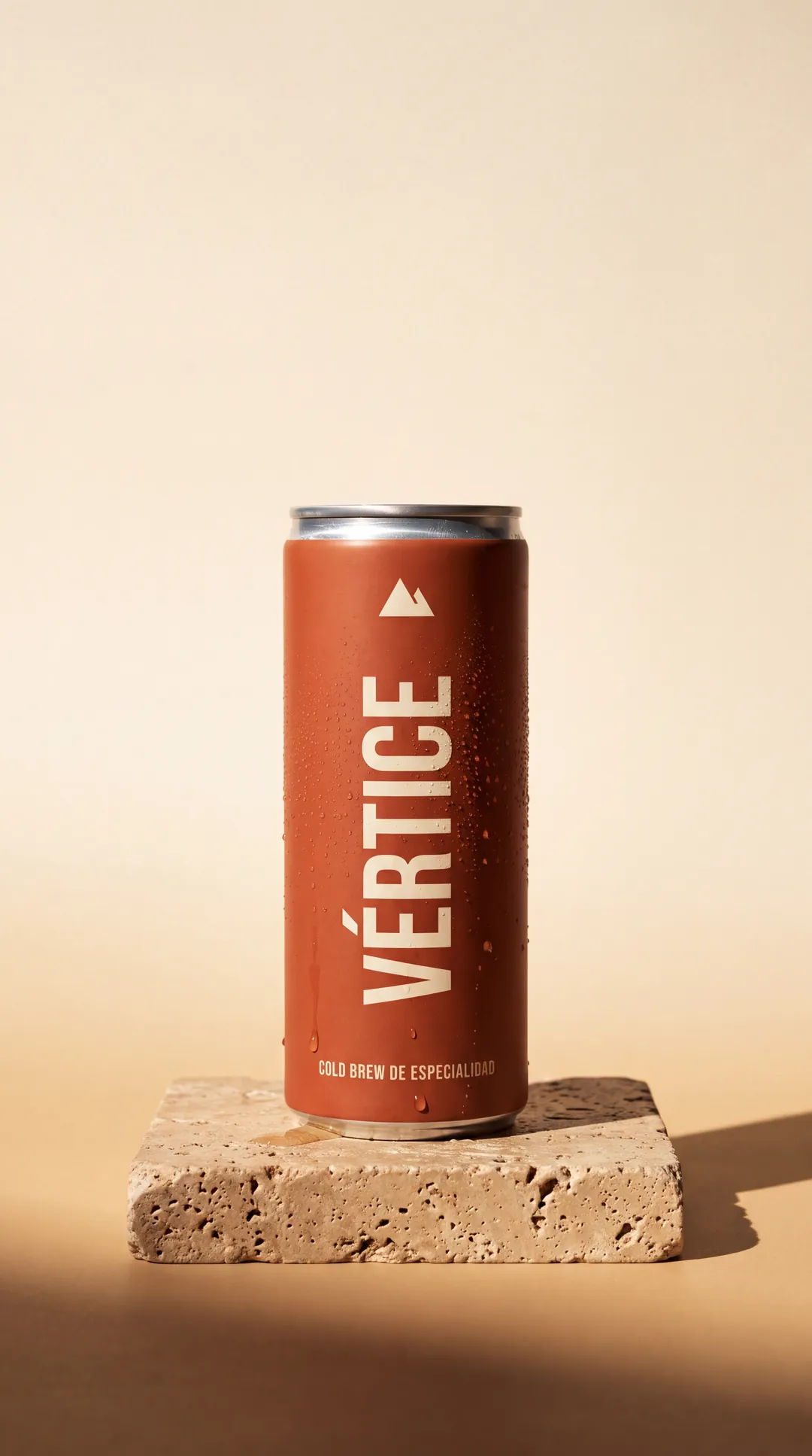 Lata terracota de VÉRTICE Cold Brew sobre una base de piedra y fondo crema